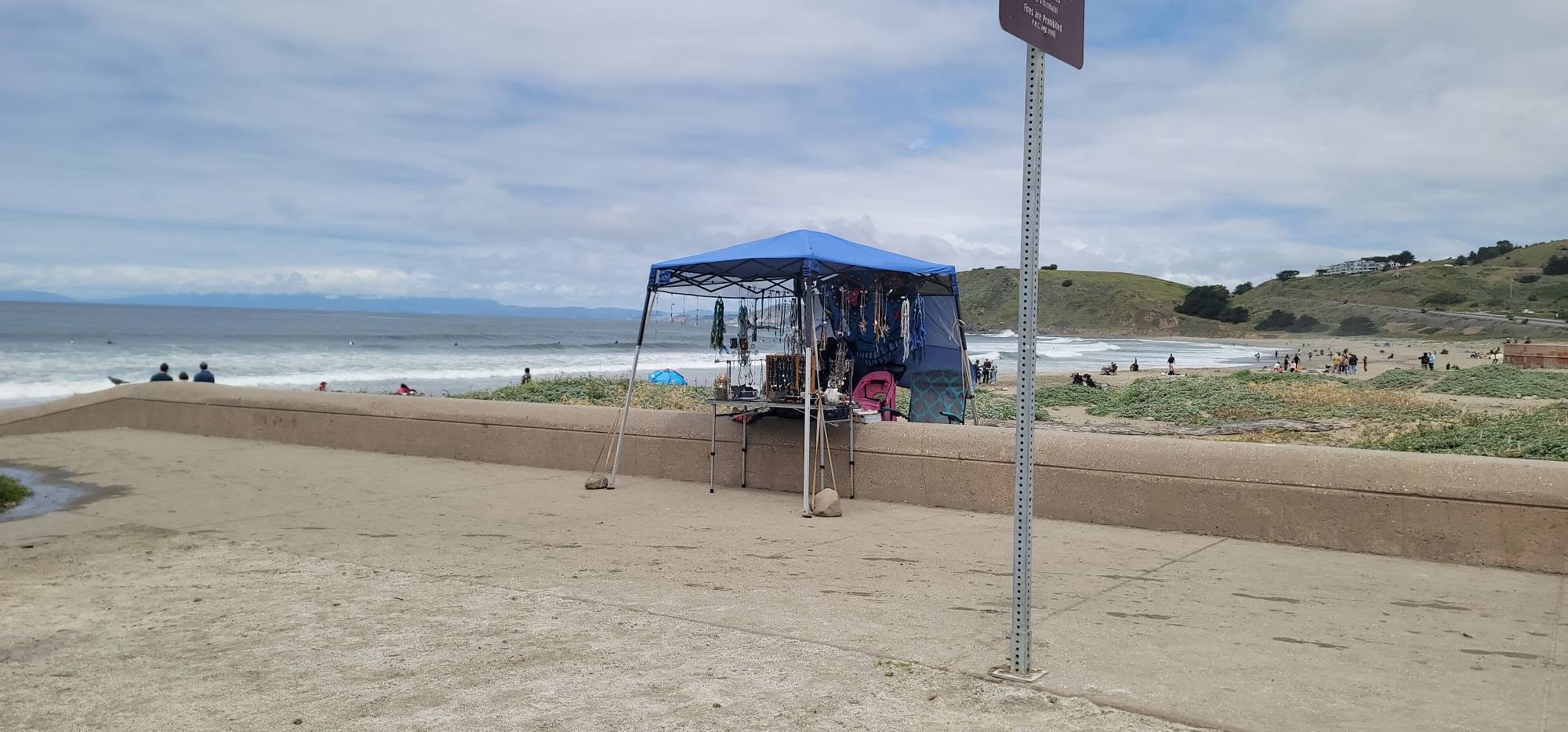 Blue tent stall on the seawall, Pacific behind it